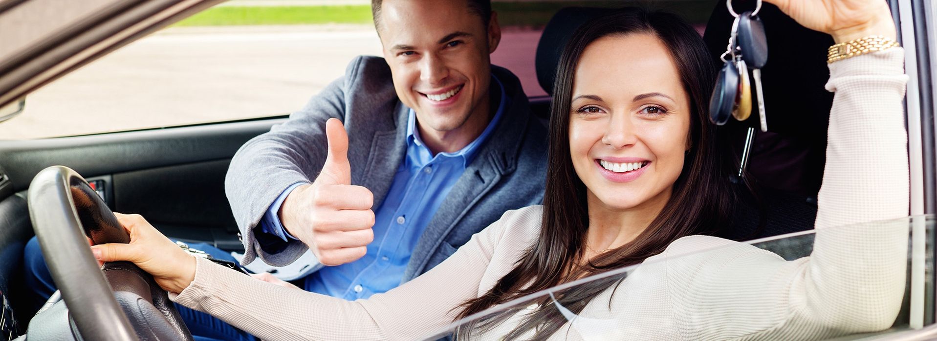 A young woman who has just passed her driving test and a driving instructor is sitting next to her